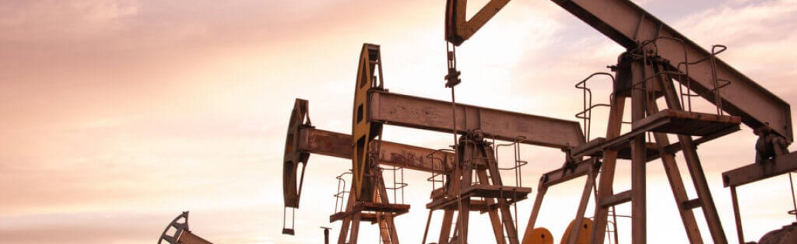 Oil pump jacks at sunset sky background. Toned.