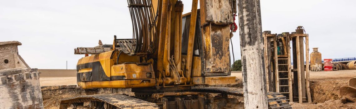 A massive drilling machine excavates soil at a construction site adjacent to an expansive open space